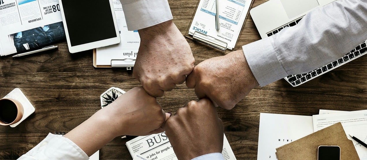 Four people fist bumping over a table